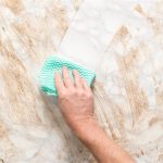Hand wiping clean a dirty marble surface with a paper towel